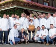 UN_GRUPPO_DI_GIOVANI_CHEF_DI_jRE_con_una_forma_di_Parmigiano_Reggiano